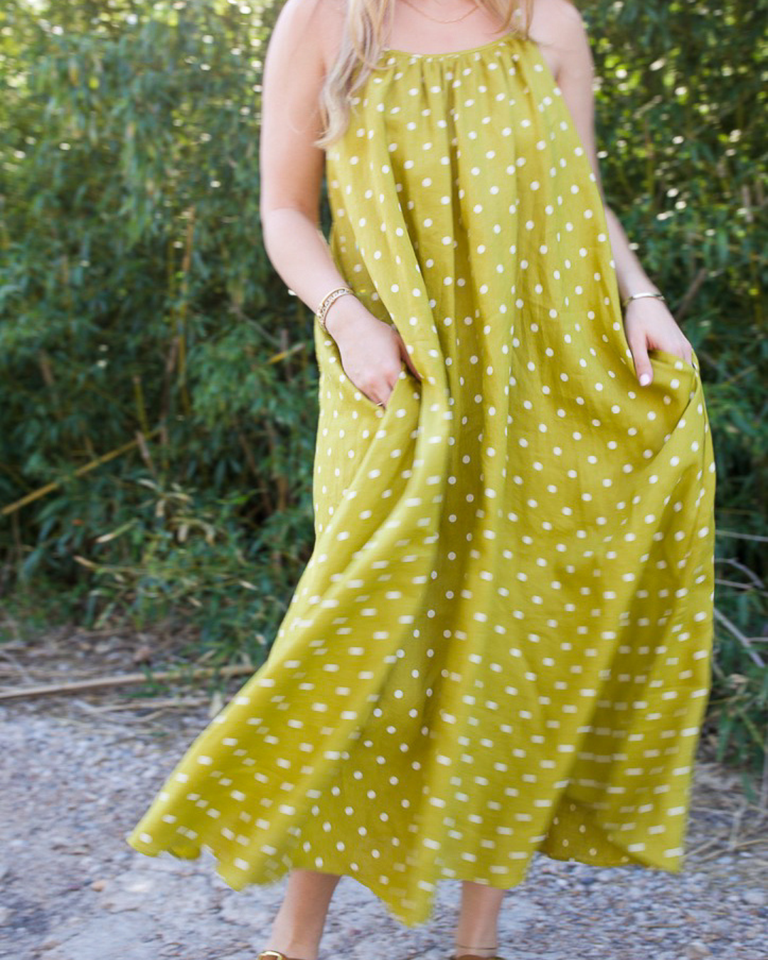 Linen polka dot tie back dress in moss green showing side pockets and flowy silhouette