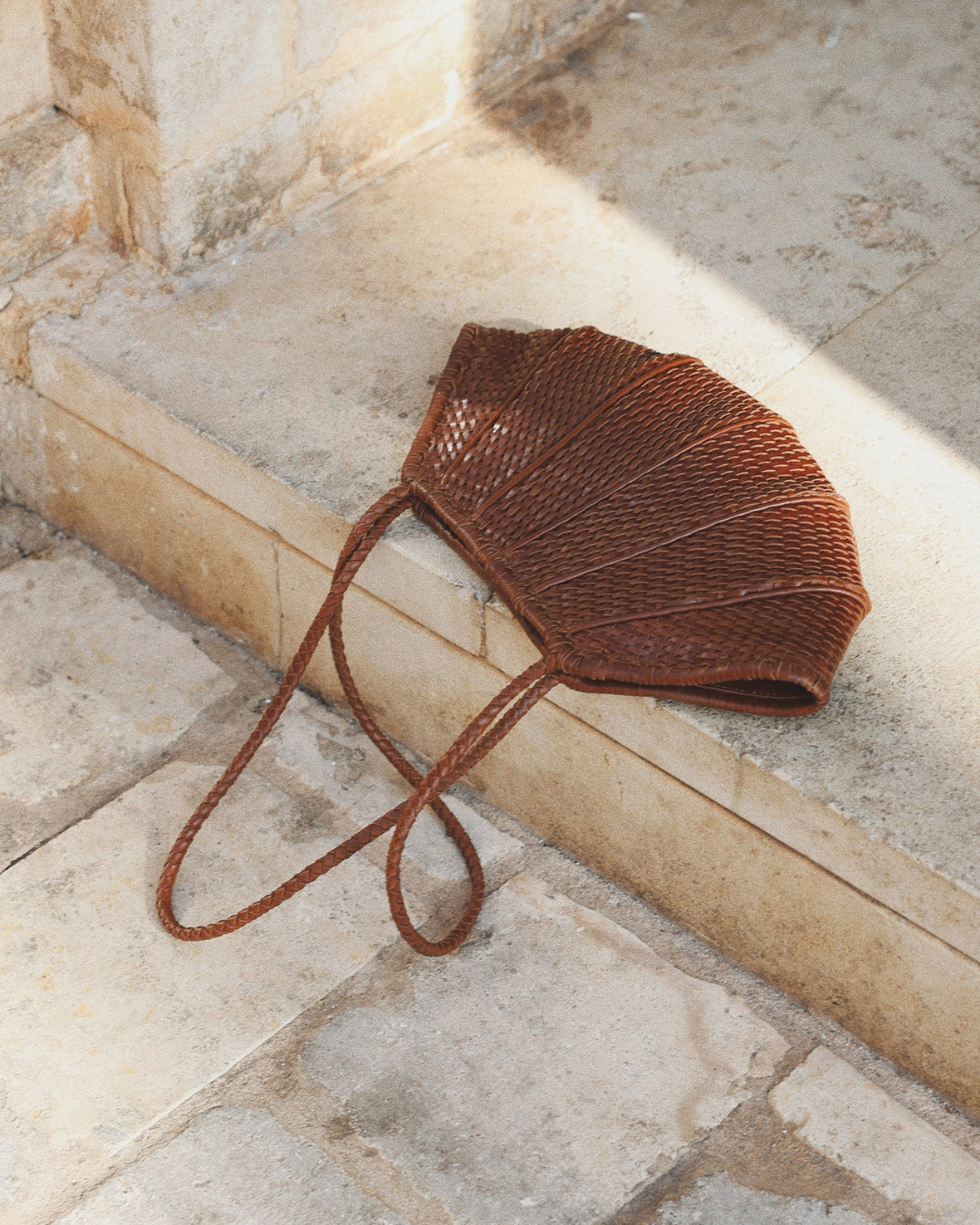 Venera Bag Sienna brown woven leather bag styled on stone steps